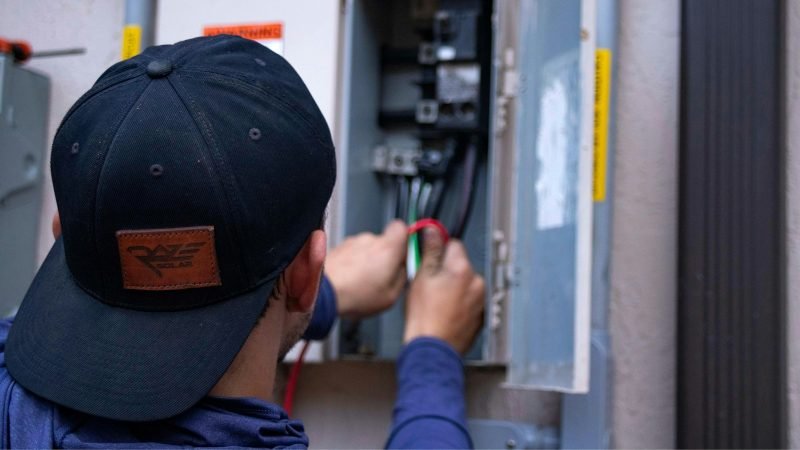 Licensed electrician installing a modern electrical breaker panel